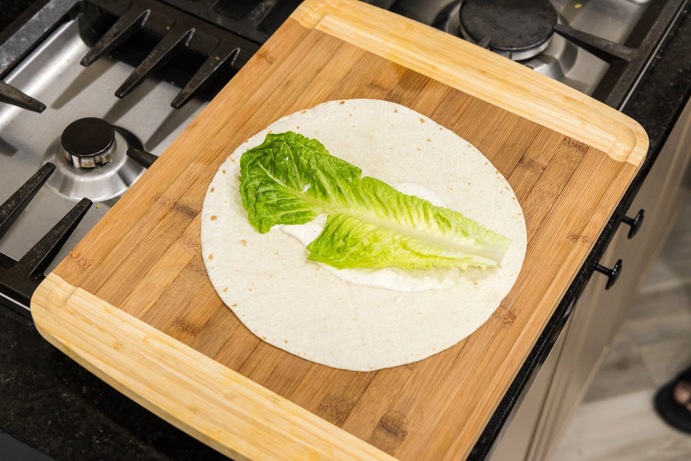 lettuce leaf on top of ranch dressing and tortilla