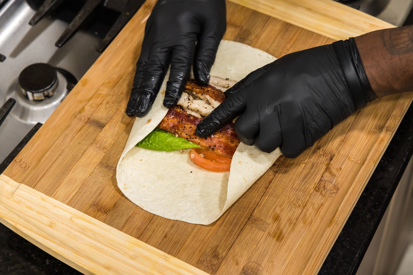 hands rolling chicken bacon ranch wrap