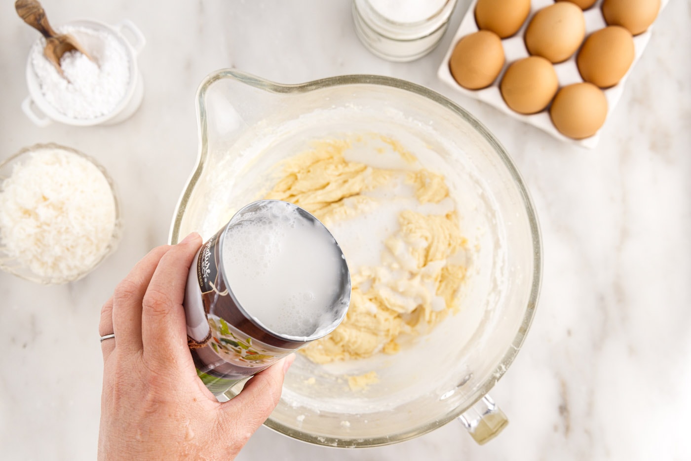 pouring coconut milk into cake batter