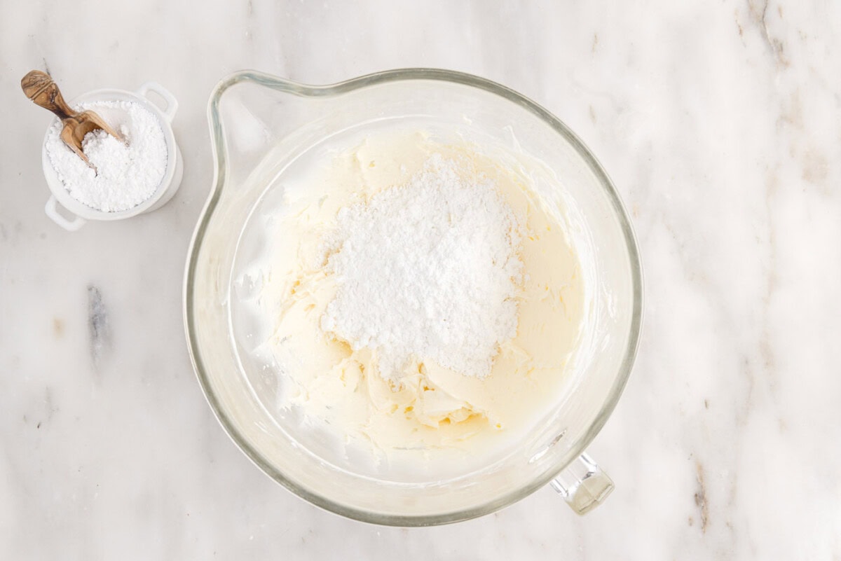 powdered sugar added to cream cheese mixture in a bowl