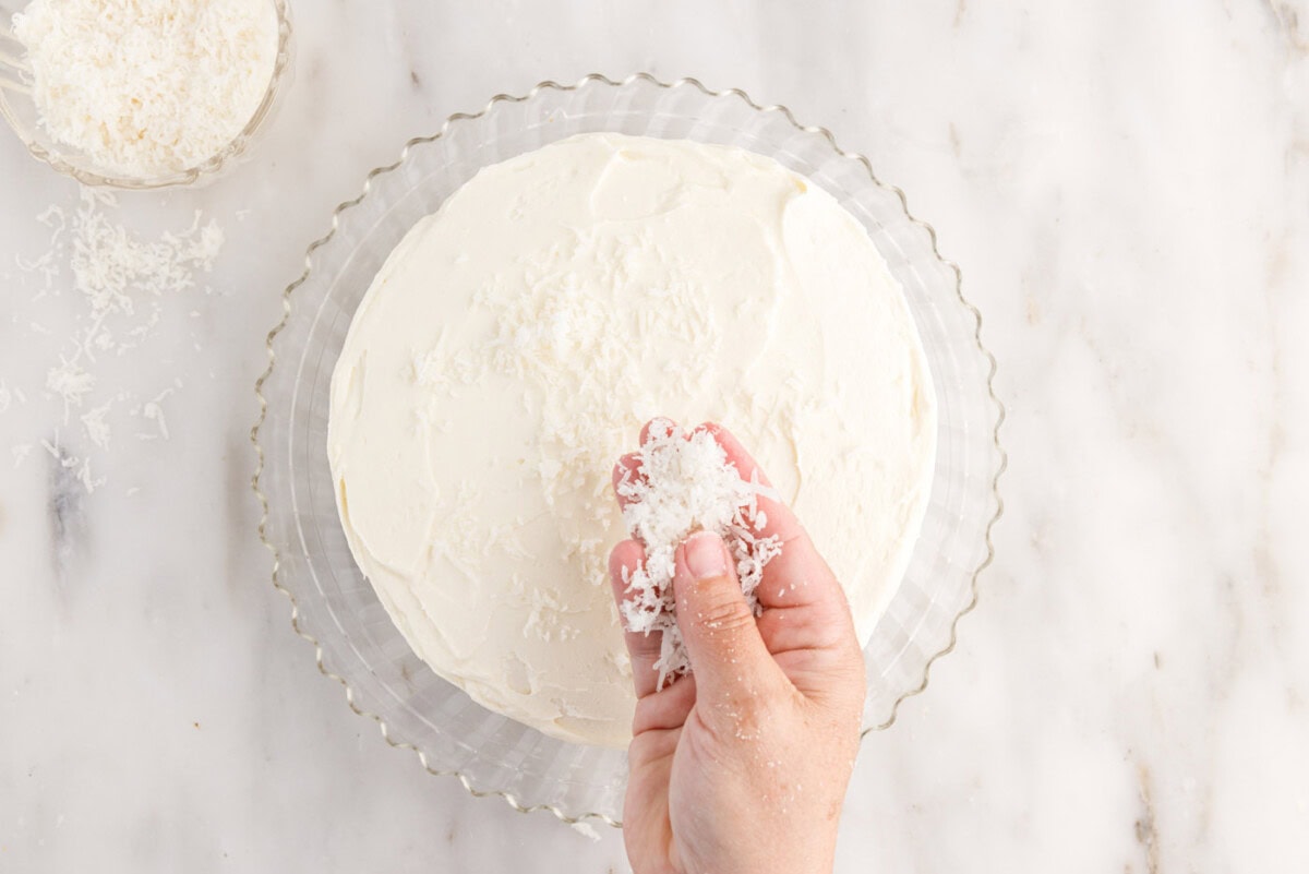sprinkling shredded coconut over frosted cake