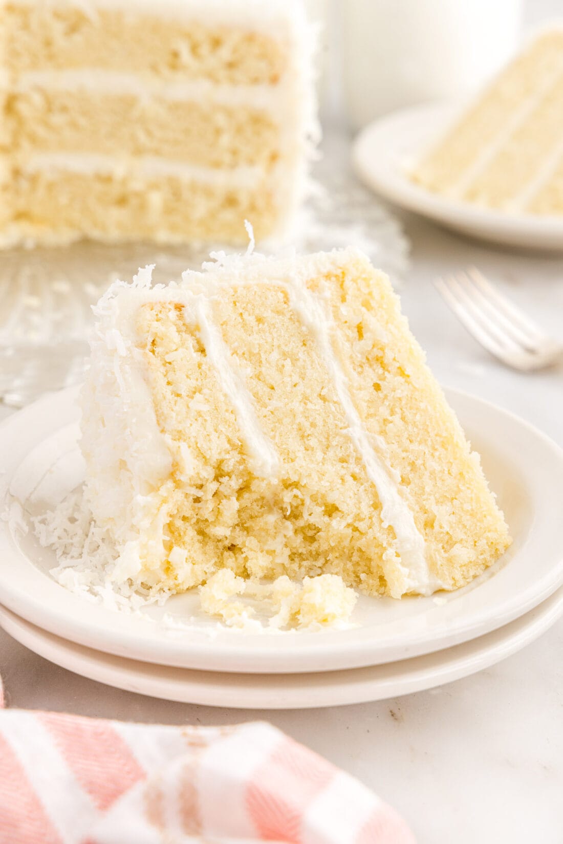 Slice of Coconut Cake on a plate with a bite removed