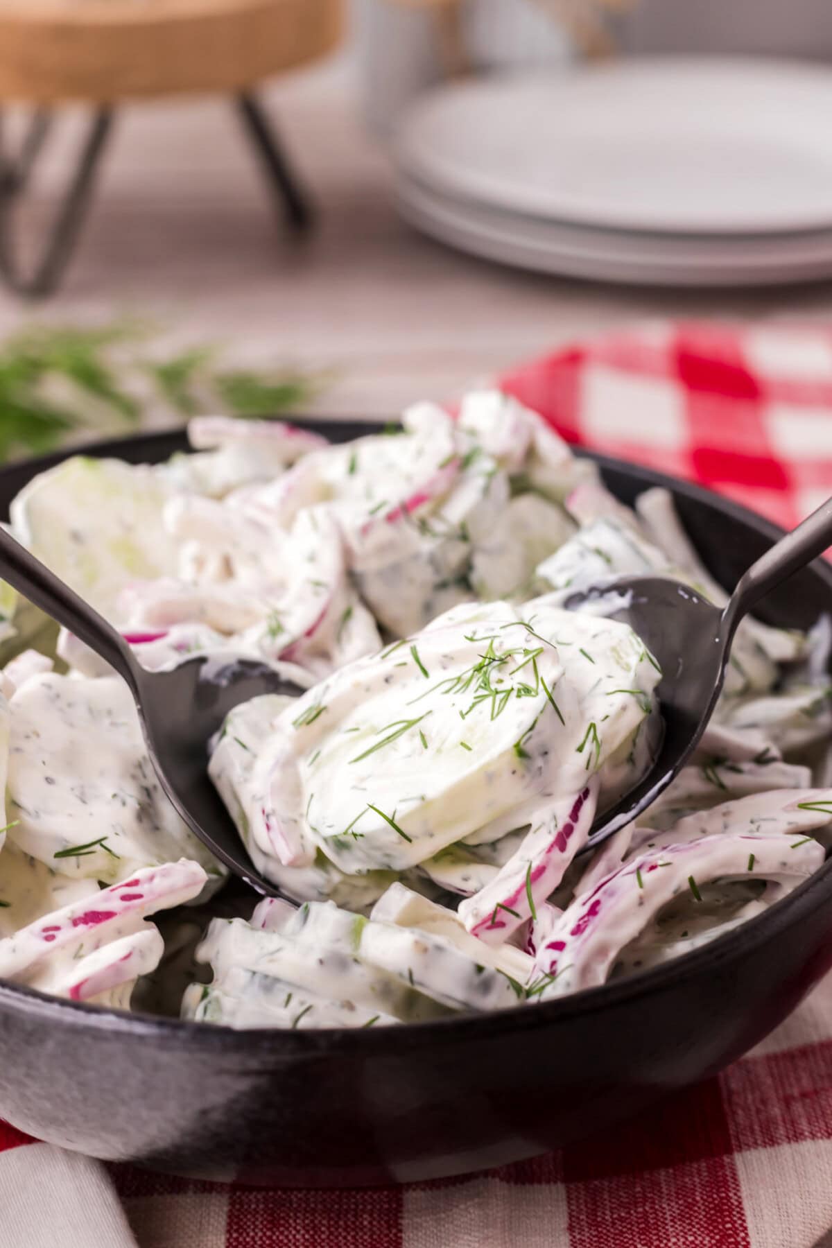 Two spoons in a bowl of Creamy Cucumber Salad