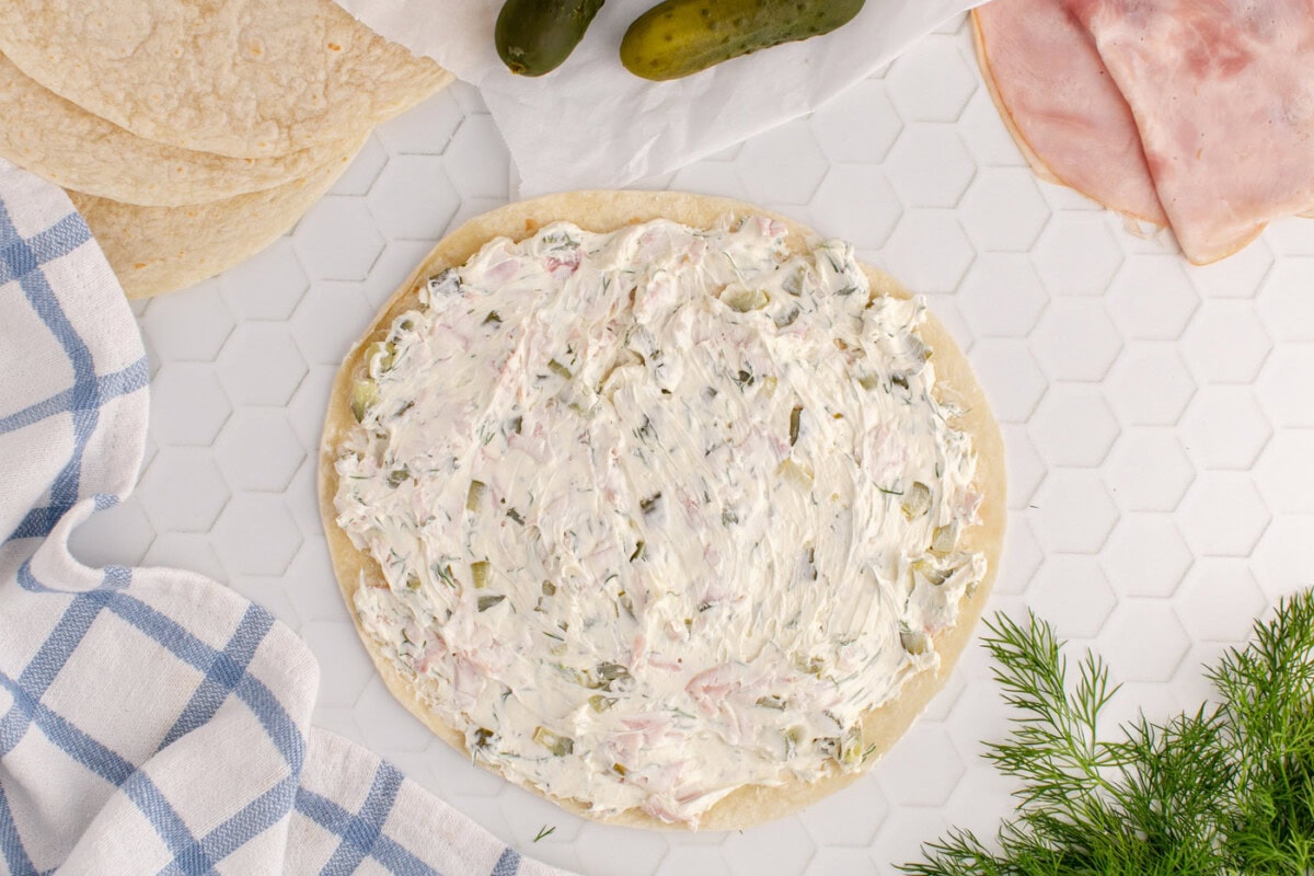 dill pickle cream cheese mixture spread onto a tortilla