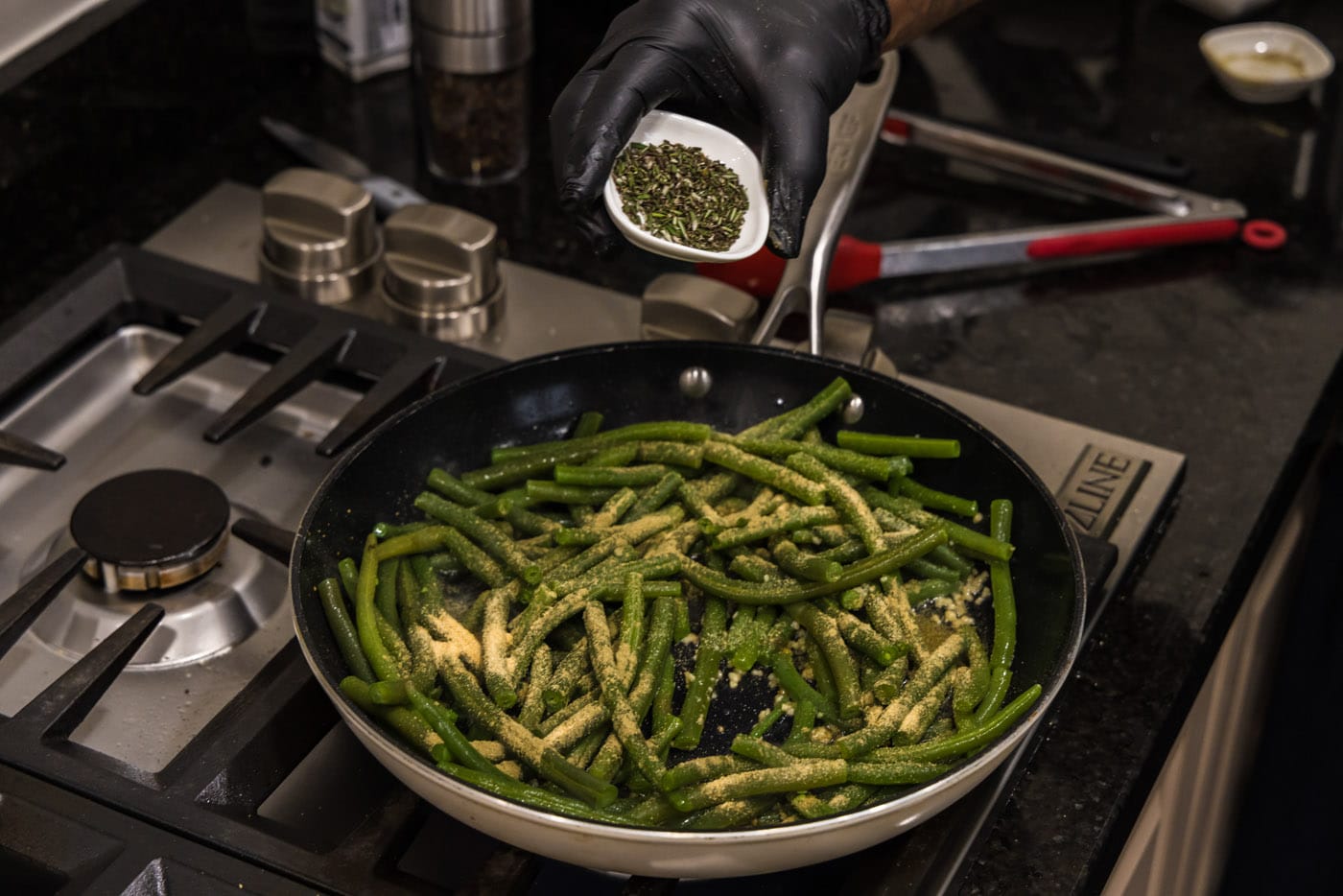 adding rosemary to skillet with green beans