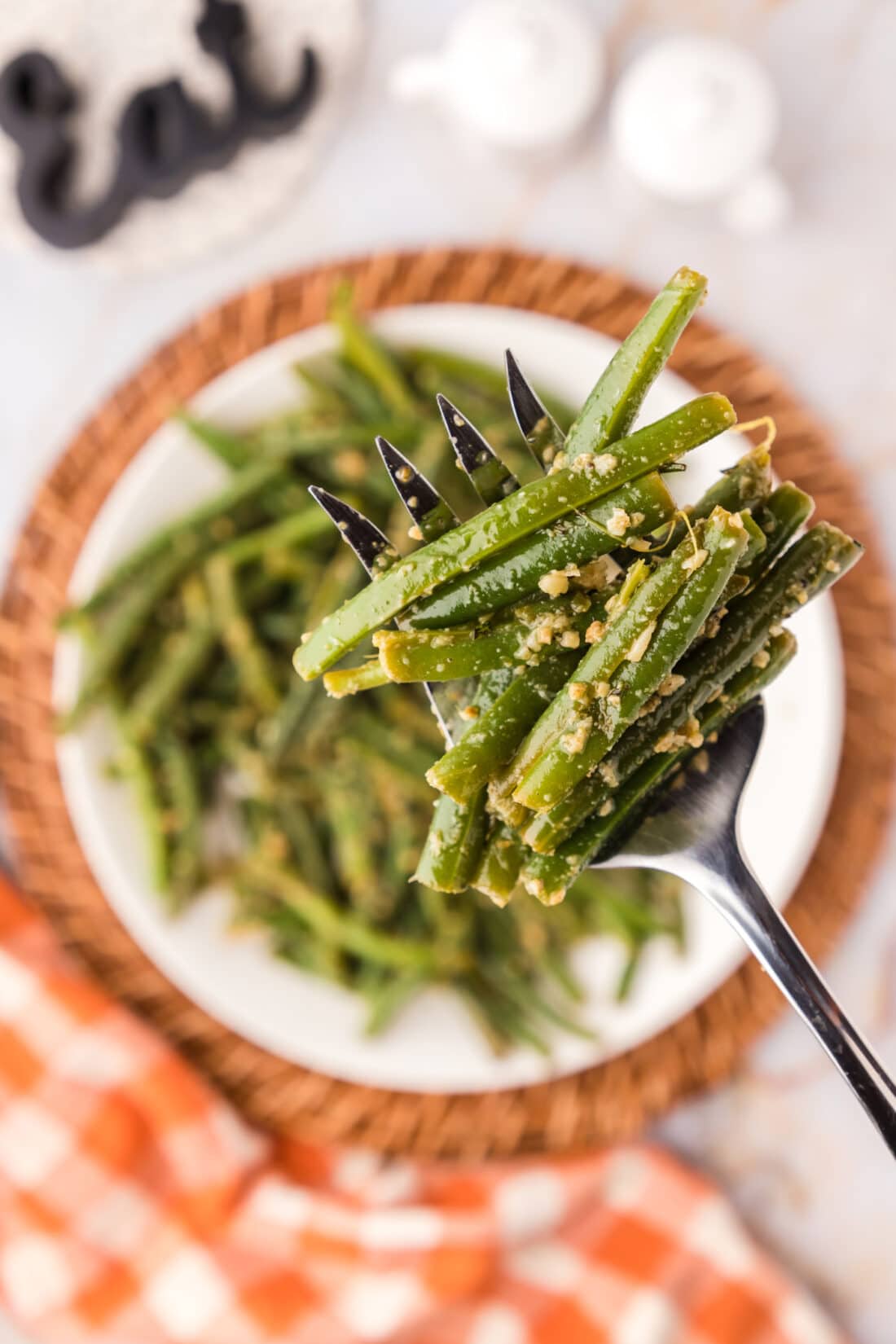 Garlic Green Beans on a fork held above a plate of Garlic Green Beans