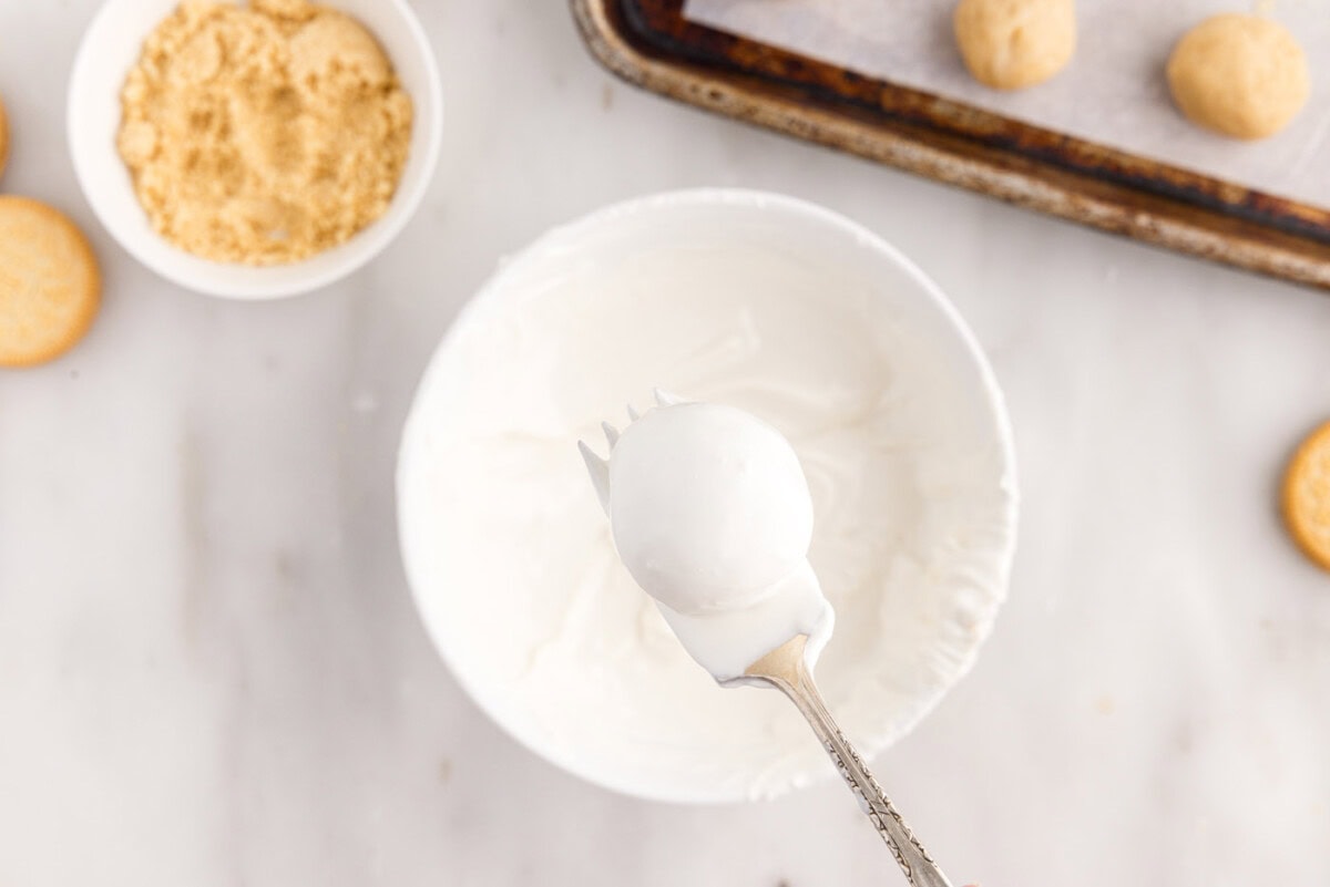 dipping Oreo truffles into white chocolate coating with a fork