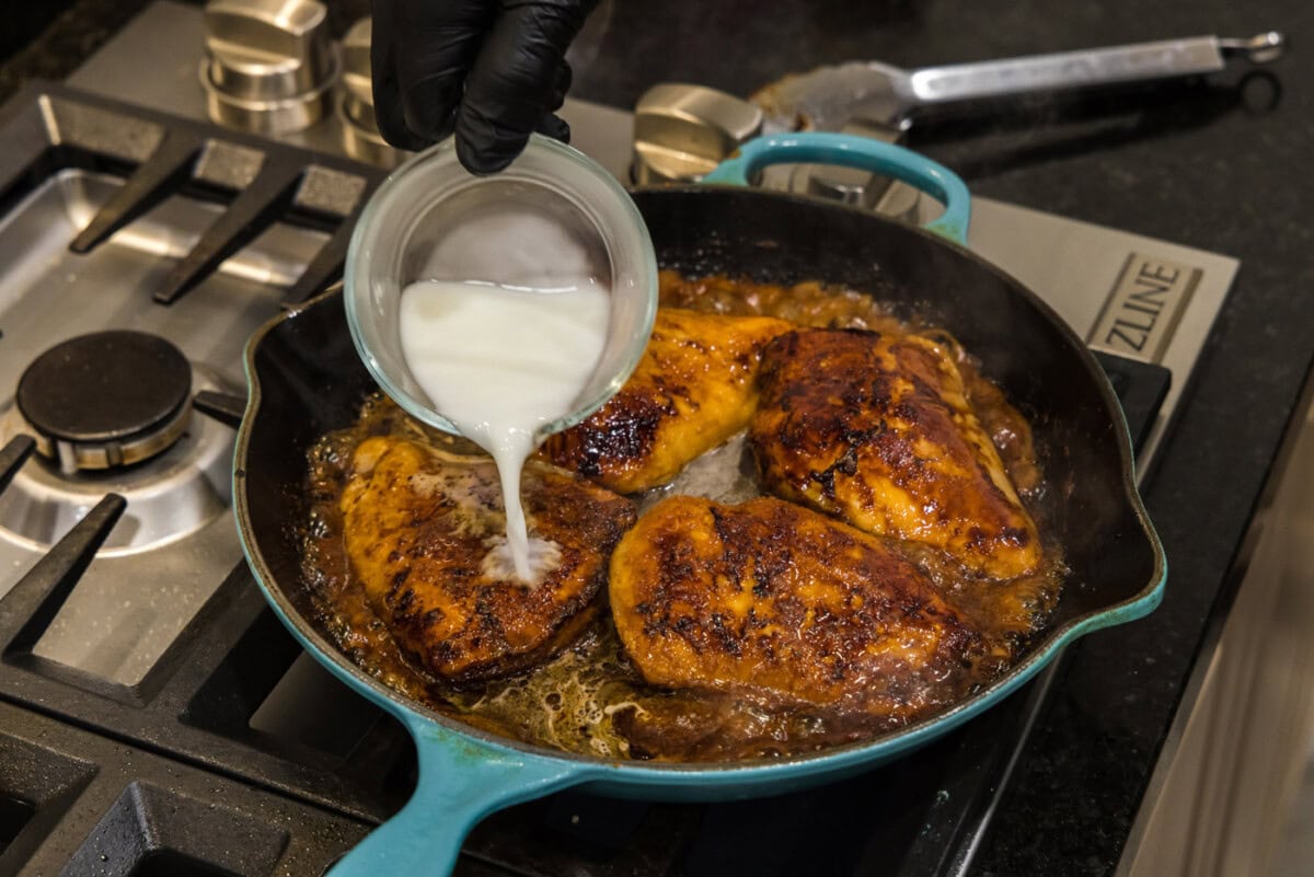 adding cornstarch slurry to skillet with chicken and sauce