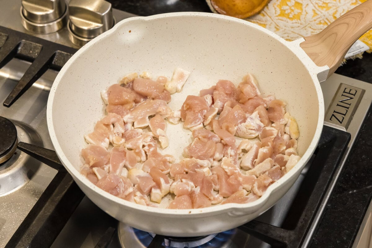 cooking sliced chicken in a skillet with oil
