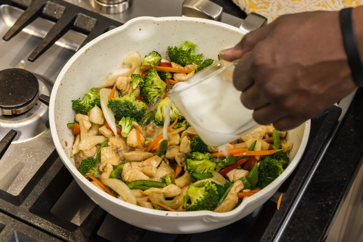 adding a cornstarch slurry to skillet of honey garlic chicken stir fry