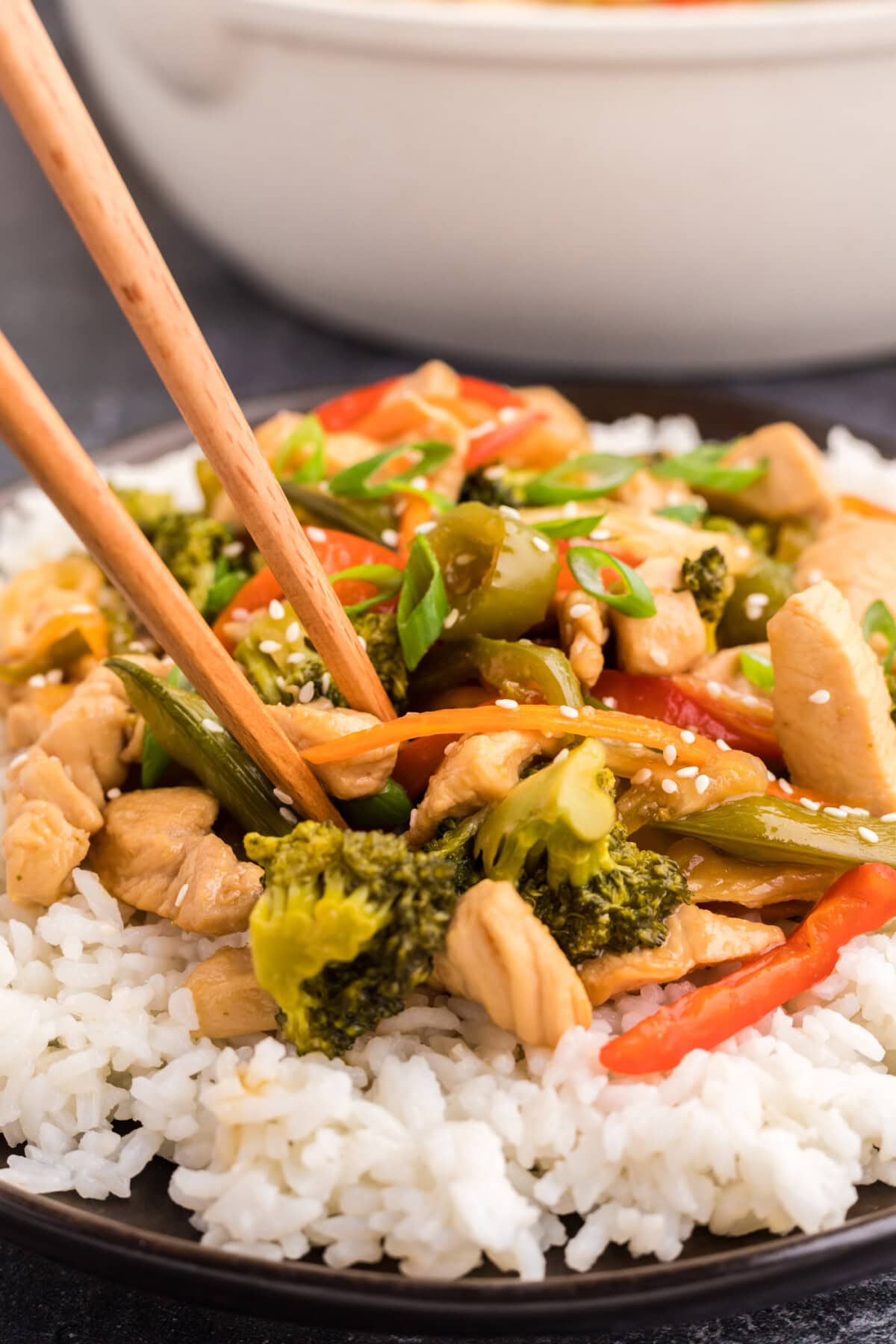 Close up photo of Honey Garlic Chicken Stir Fry on a plate over rice with chopsticks