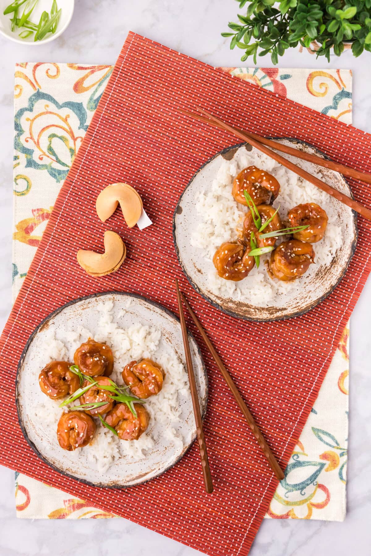 Two plates of Hunan Shrimp with chopsticks and fortune cookies