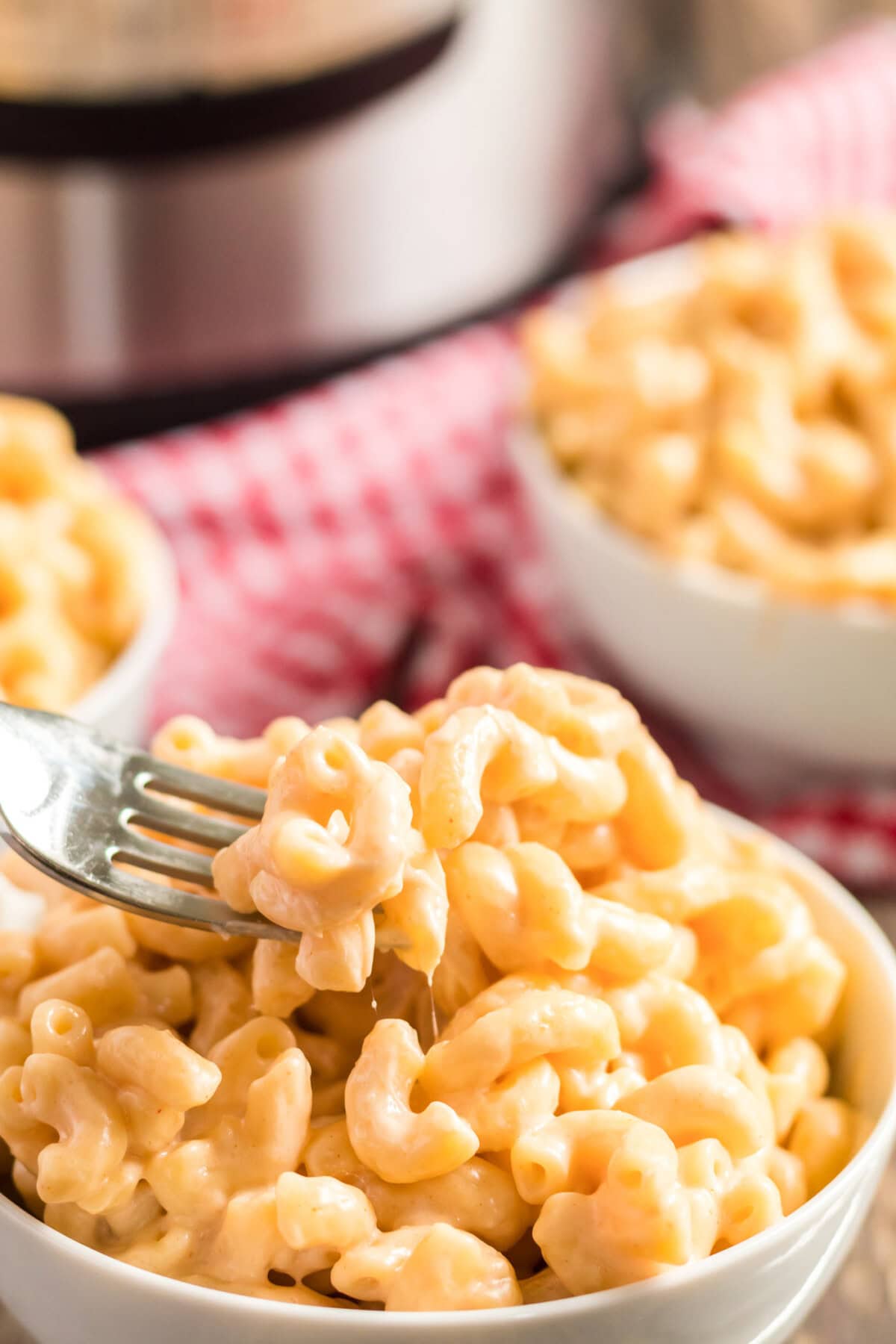 Creamy, delicious Instant Pot mac and cheese. If you're wondering how to make macaroni and cheese in your Instant Pot, I'm going to show you how to do it with just 5 minutes of cooking time. This Instant Pot mac and cheese is easy to make and it's super creamy and delicious! #macandcheese #macaroniandcheese #instantpot #instantpotmacandcheese #cheddarcheese #mozzarella #creamcheese #elbowmacaroni Fork in a bowl of Instant Pot Mac and Cheese