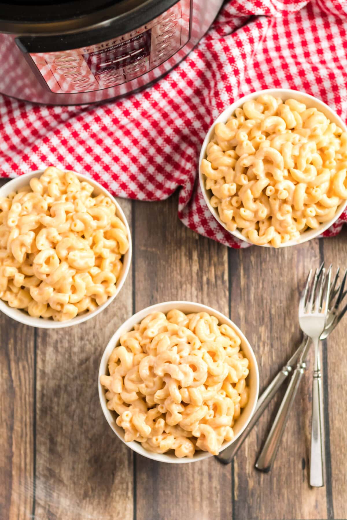 Creamy, delicious Instant Pot mac and cheese. If you're wondering how to make macaroni and cheese in your Instant Pot, I'm going to show you how to do it with just 5 minutes of cooking time. This Instant Pot mac and cheese is easy to make and it's super creamy and delicious! #macandcheese #macaroniandcheese #instantpot #instantpotmacandcheese #cheddarcheese #mozzarella #creamcheese #elbowmacaroni Three bowls of Instant Pot Mac and Cheese