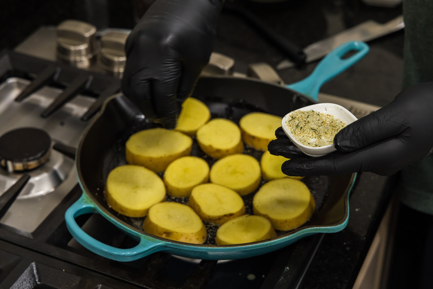 seasoning potato rounds in a skillet