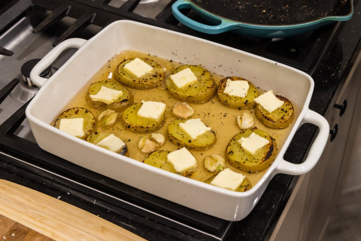 pats of butter on top of potato slices cooked in chicken broth