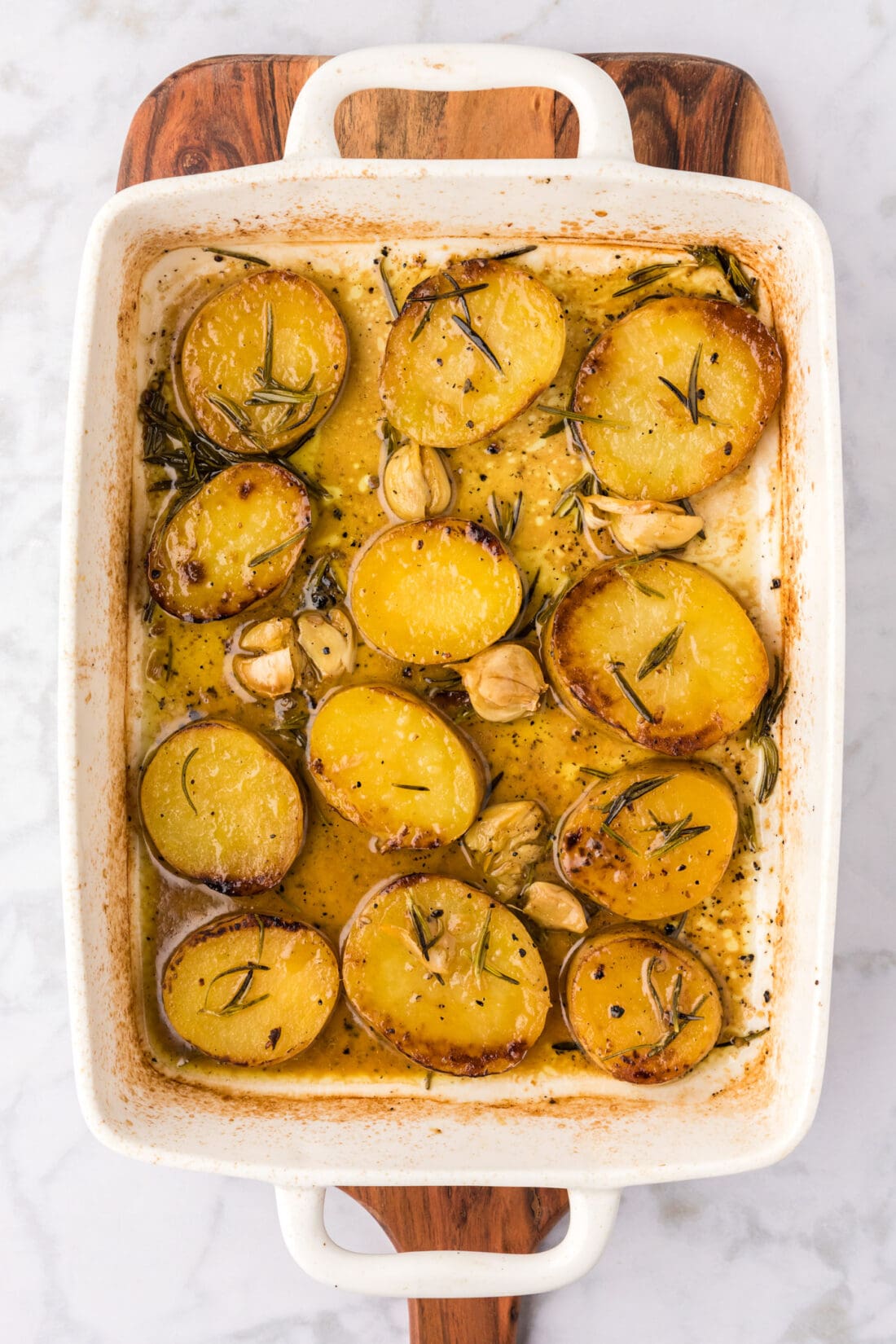 Baking dish of Melting Potatoes resting on a wooden platter