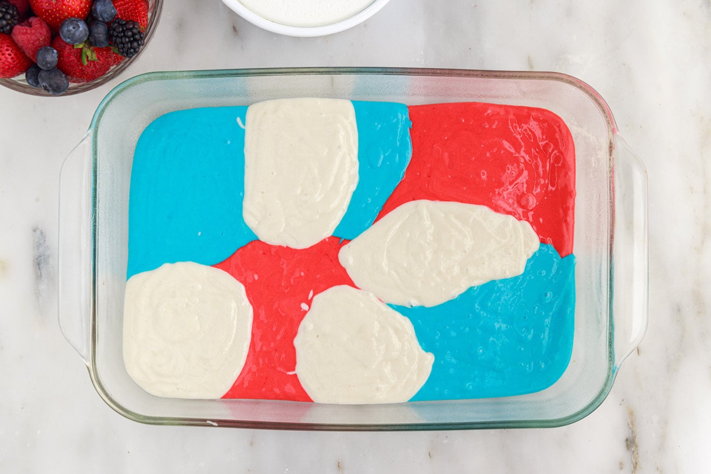 dollops of red white and blue cake batter in a baking dish