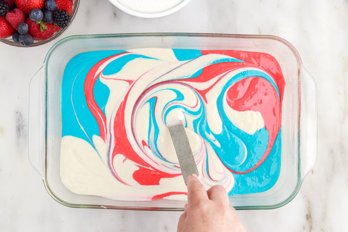 using an icing spatula to swirl cake batter colors together