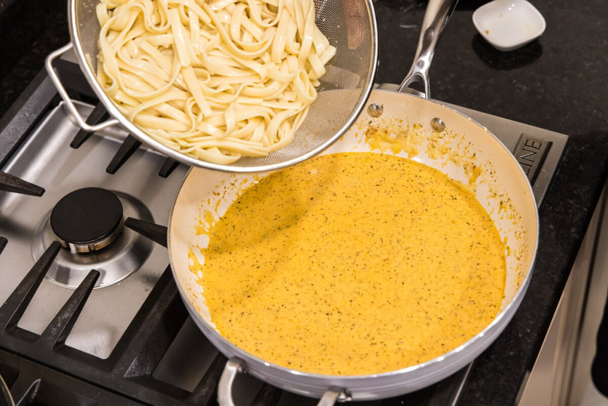 adding noodles to alfredo sauce