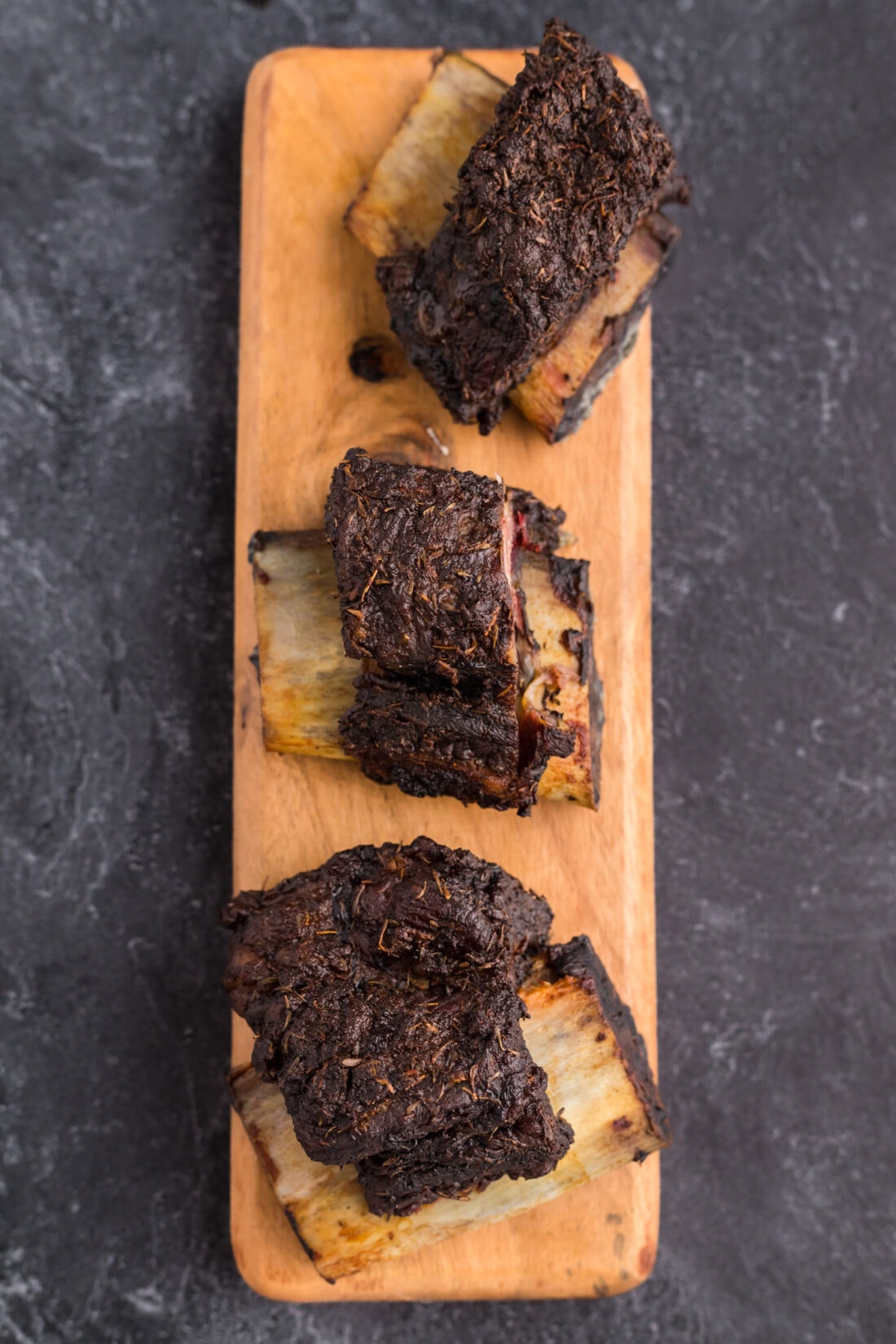 Three Smoked Beef Short Ribs on a wooden serving platter
