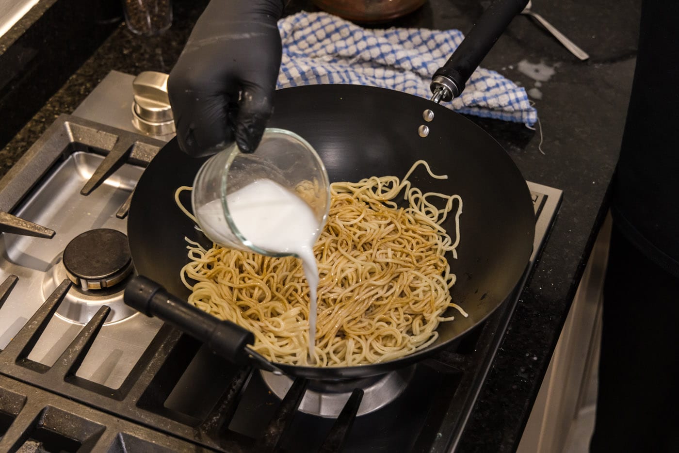 pouring a cornstarch slurry into teriyaki noodles