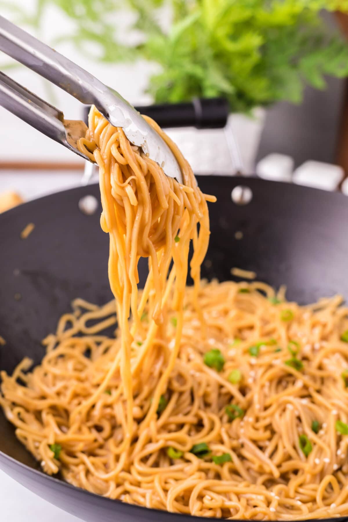 Tongs picking up Teriyaki Noodles from a wok