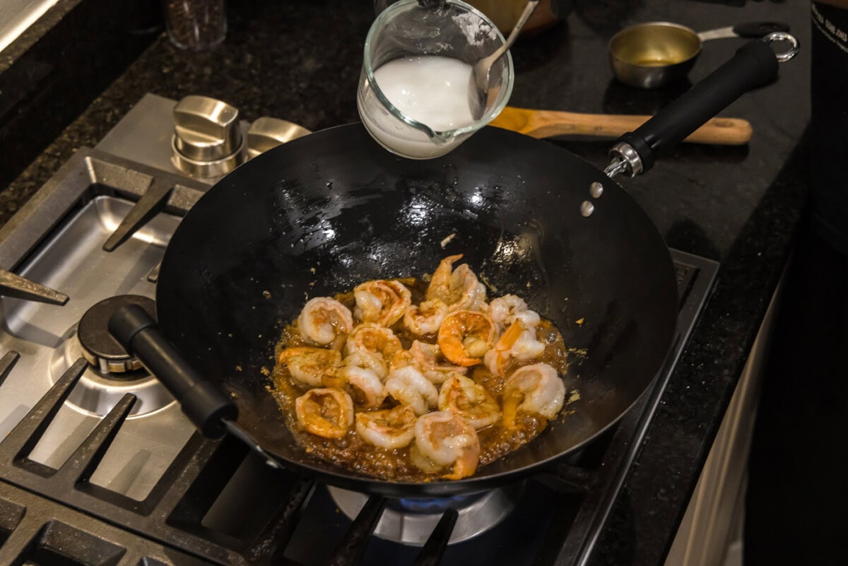 pouring a cornstarch slurry into teriyaki shrimp