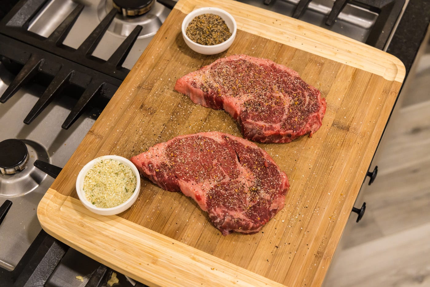ribeye steaks on cutting board seasoned with garlic salt and steak seasoning