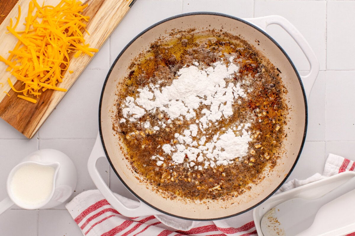 adding flour to skillet with butter and garlic