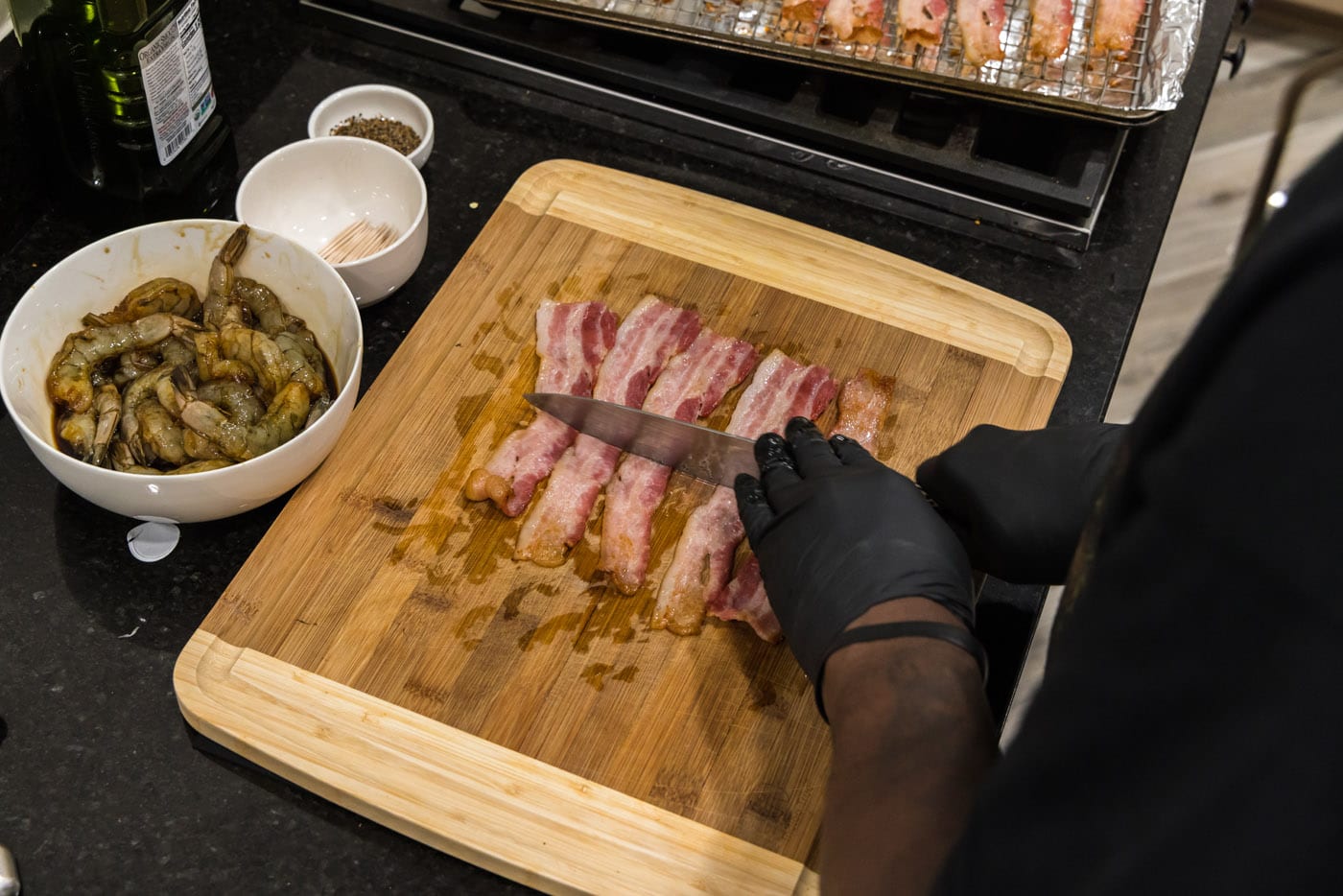 slicing bacon in half on a cutting board