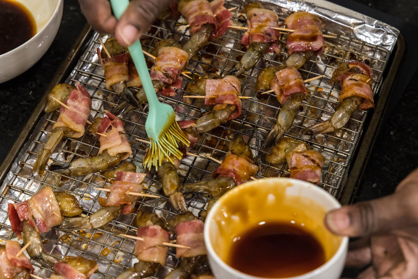 brushing glaze over bacon wrapped shrimp