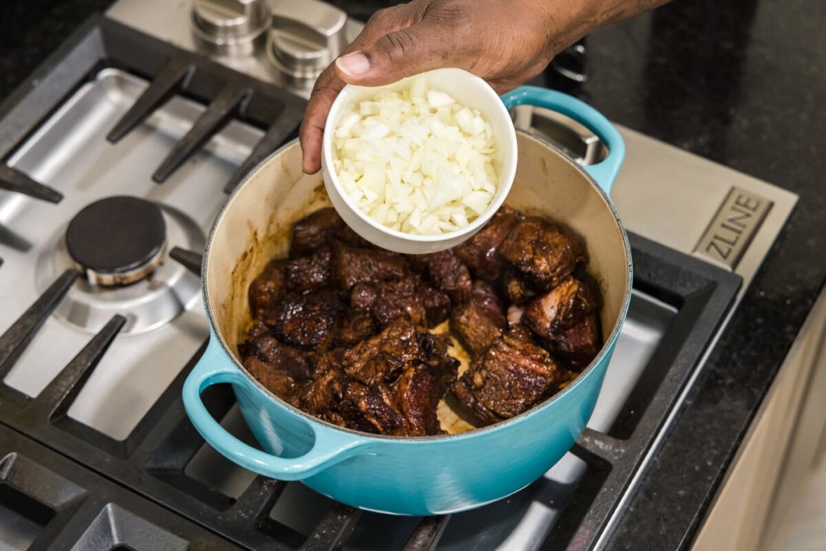 adding onion to dutch oven with beef tips