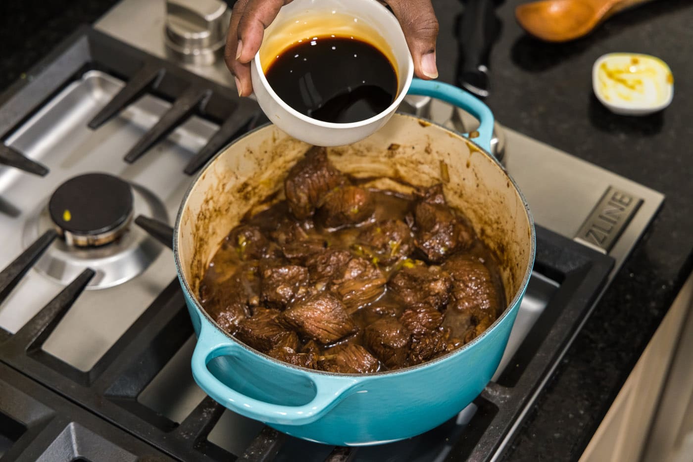 pouring soy sauce into pot with beef tips