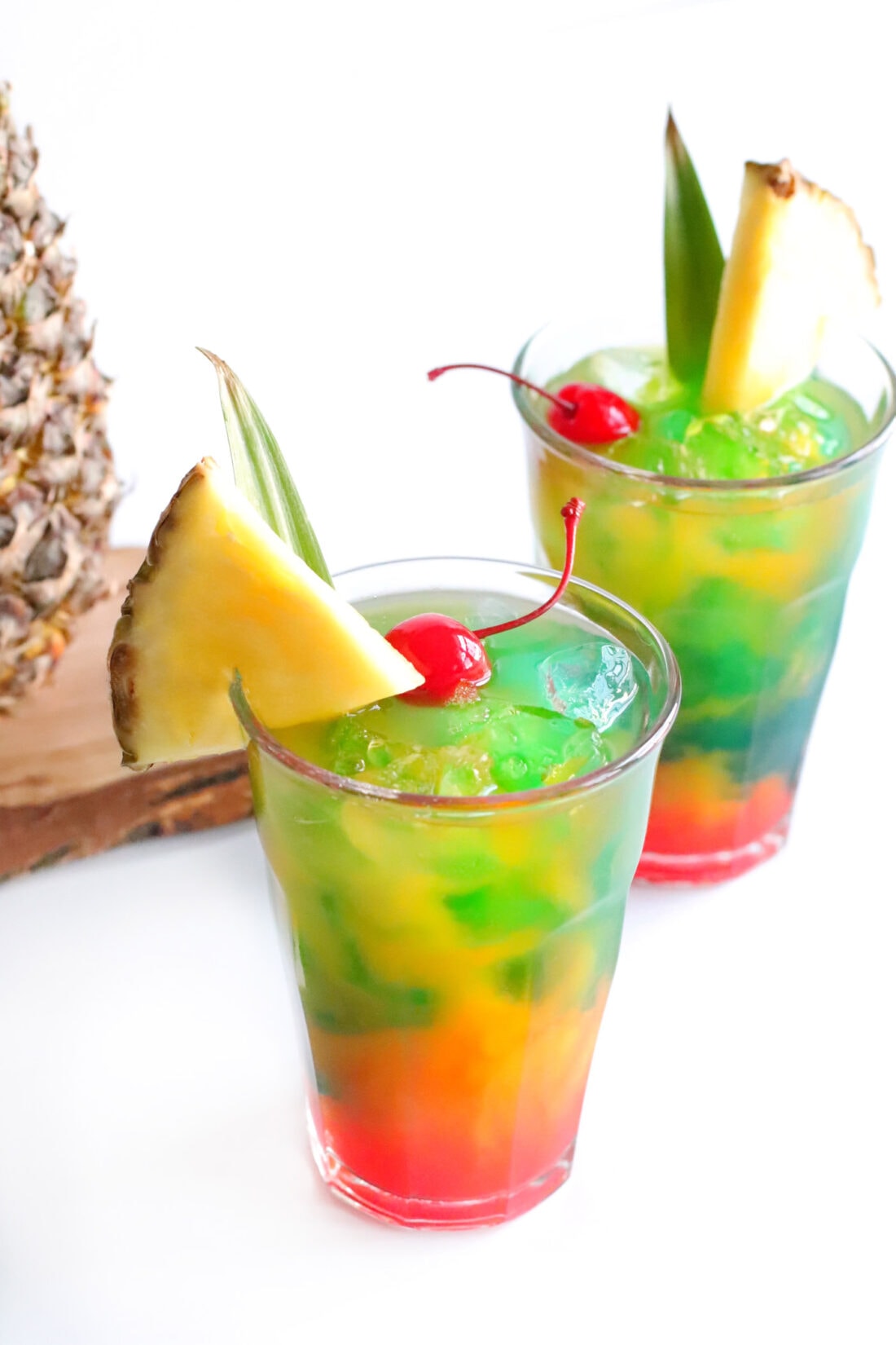 Two Blue Hawaiian Mai Tai drinks garnished with a pineapple wedge and cherry