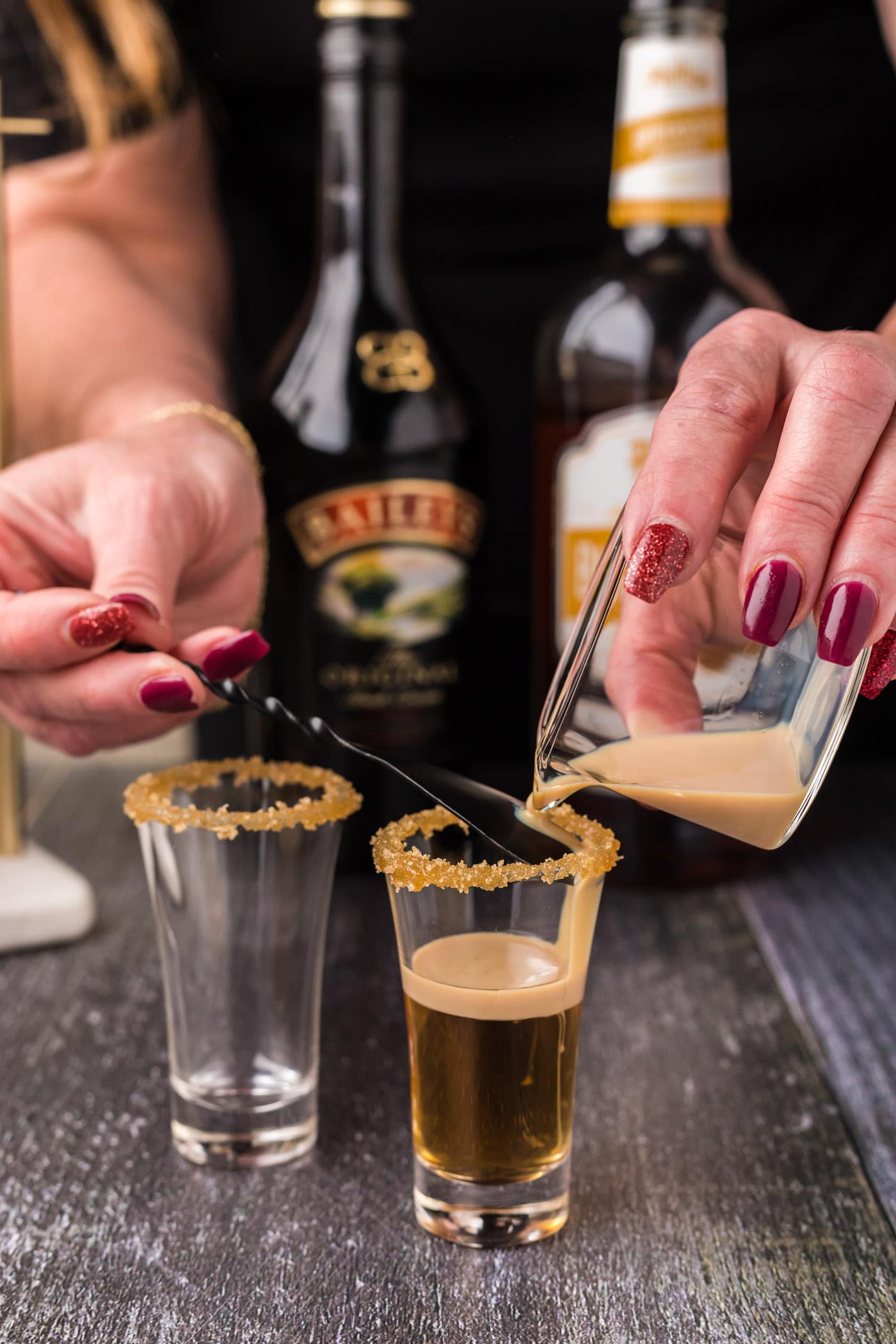 gently pouring irish cream over butterscotch schnapps in a shot glass