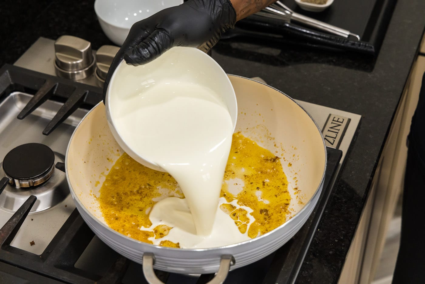 pouring heavy whipping cream into skillet with shrimp drippings