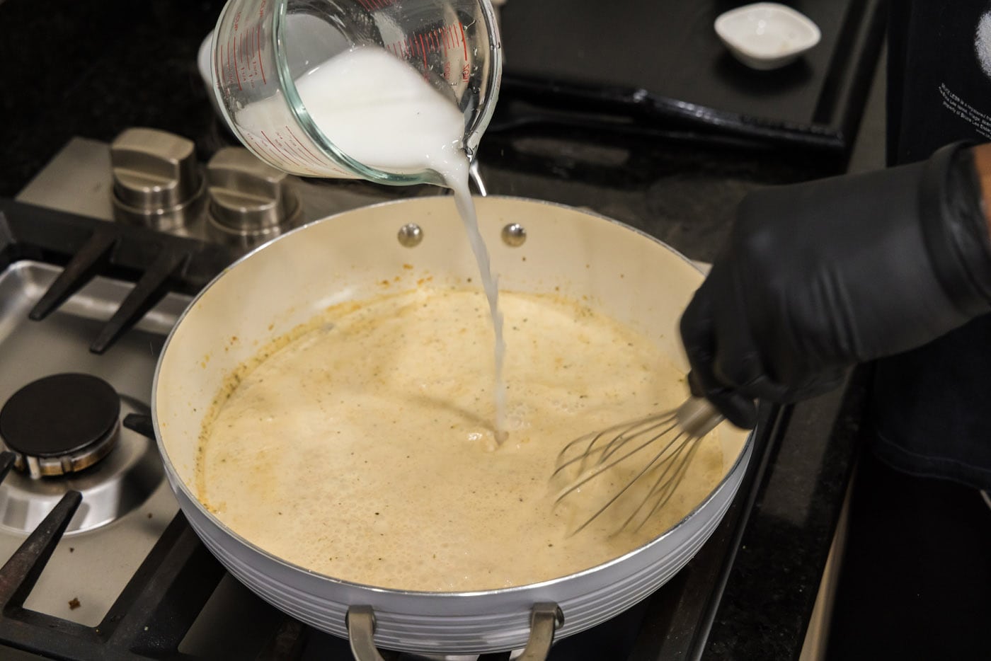 pouring cornstarch slurry in to sauce to thicken