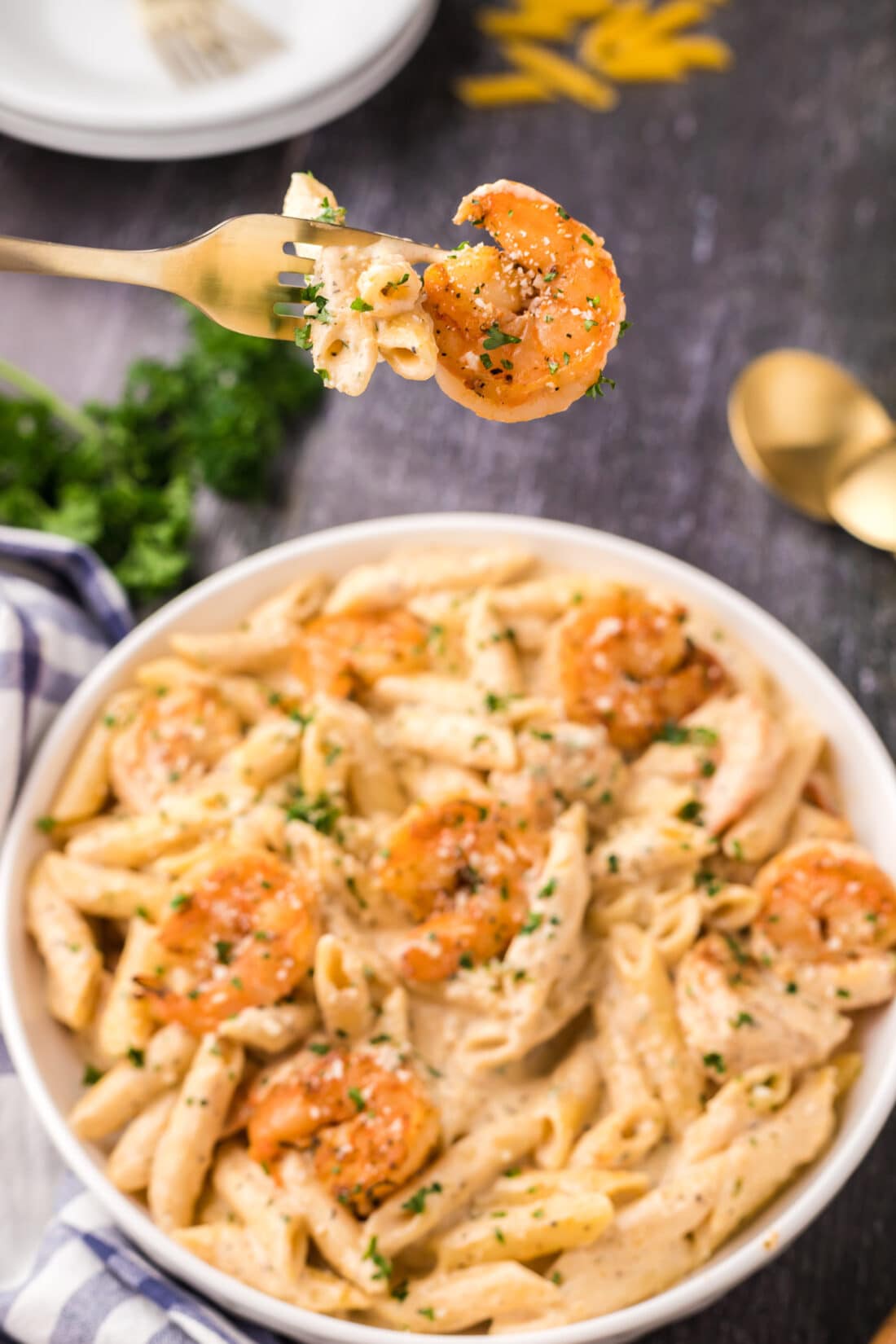 Cajun Shrimp Pasta on a fork held above a bowl of Cajun Shrimp Pasta