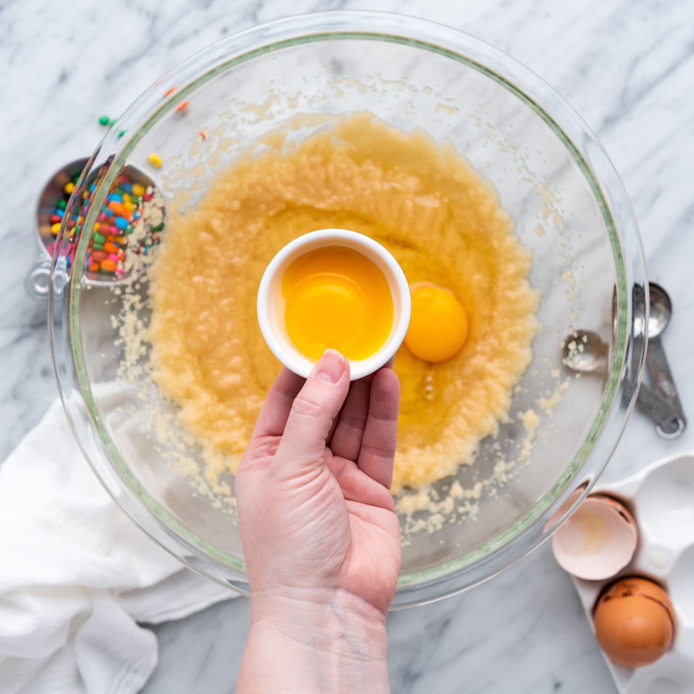 adding egg yolks to brownie batter in a bowl
