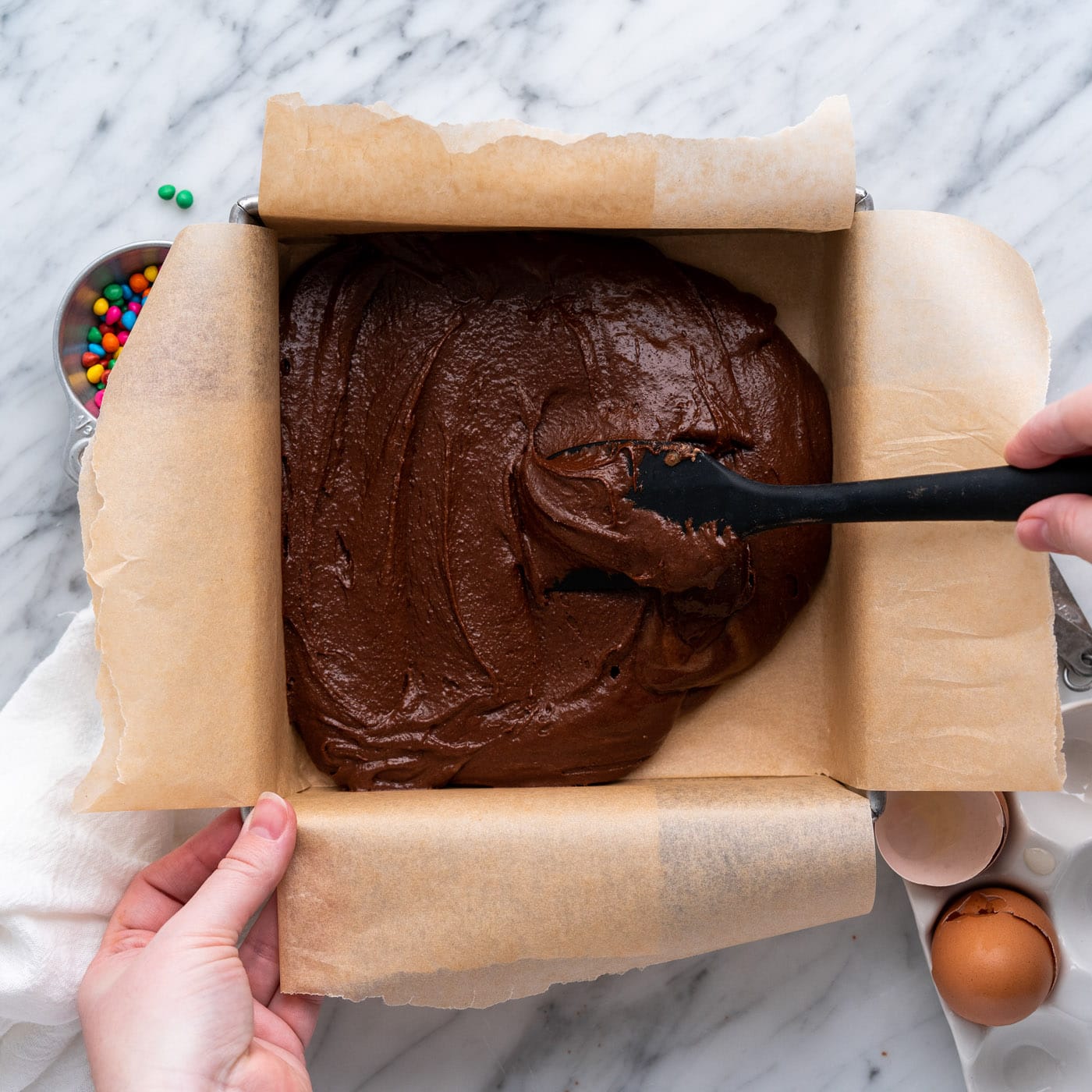 spreading brownie batter in a baking pan