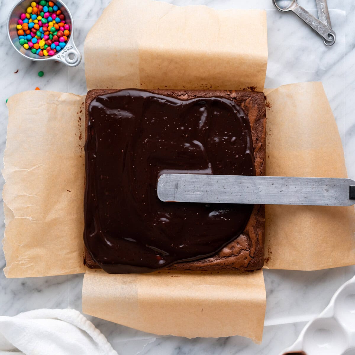 spreading ganache over brownies in a pan