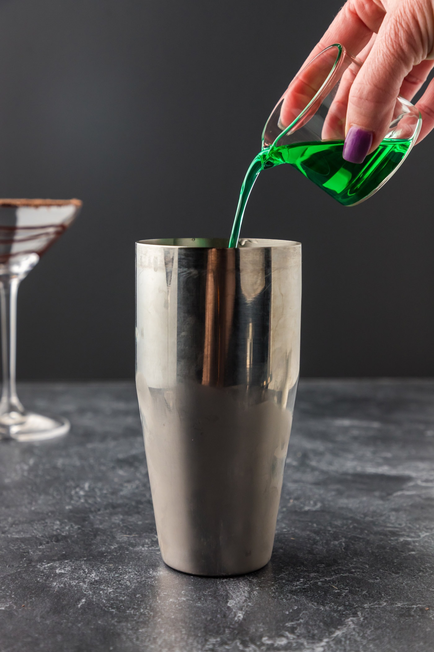 pouring creme de menthe into cocktail shaker