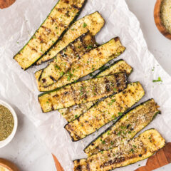 Grilled Zucchini on a wooden platter topped with parmesan cheese