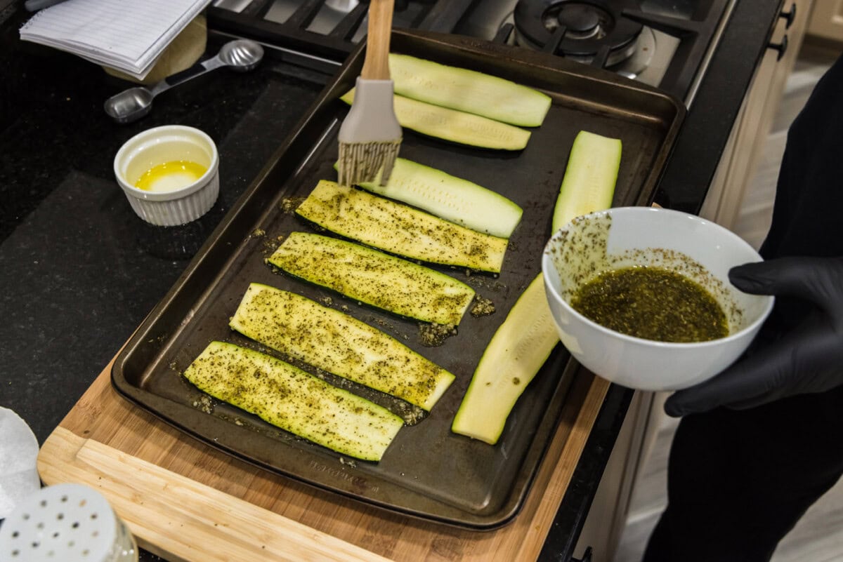 brushing oil and seasonings onto sliced zucchini