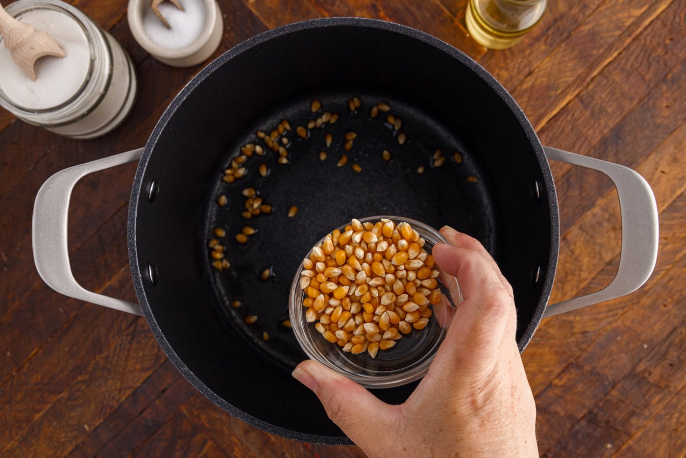 adding corn kernels to oil in a pot