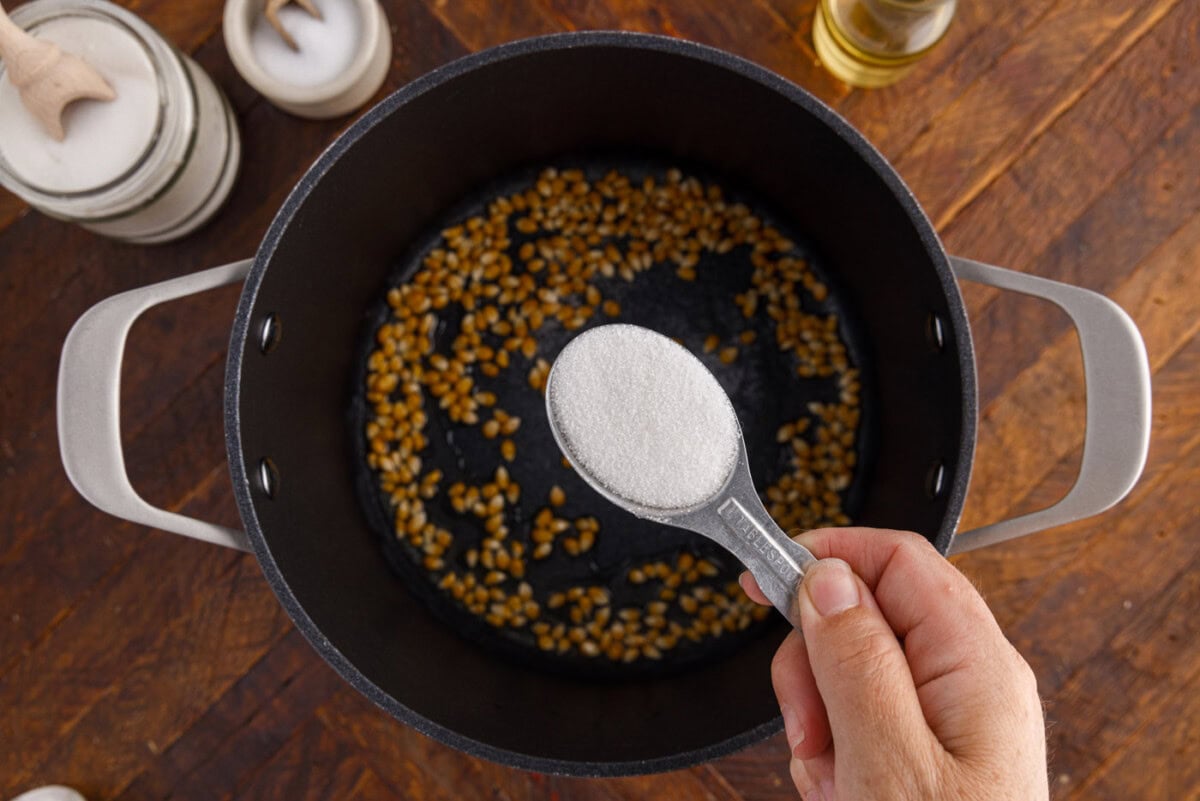 sprinkling sugar over corn kernels