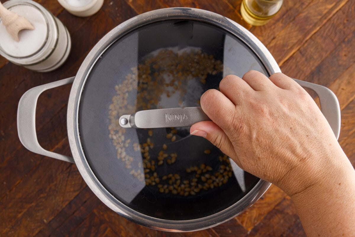 placing lid over popcorn in a pot