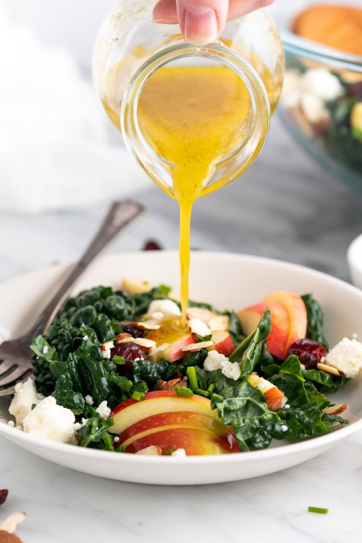 Lemon Salad Dressing being poured over a Kale Salad