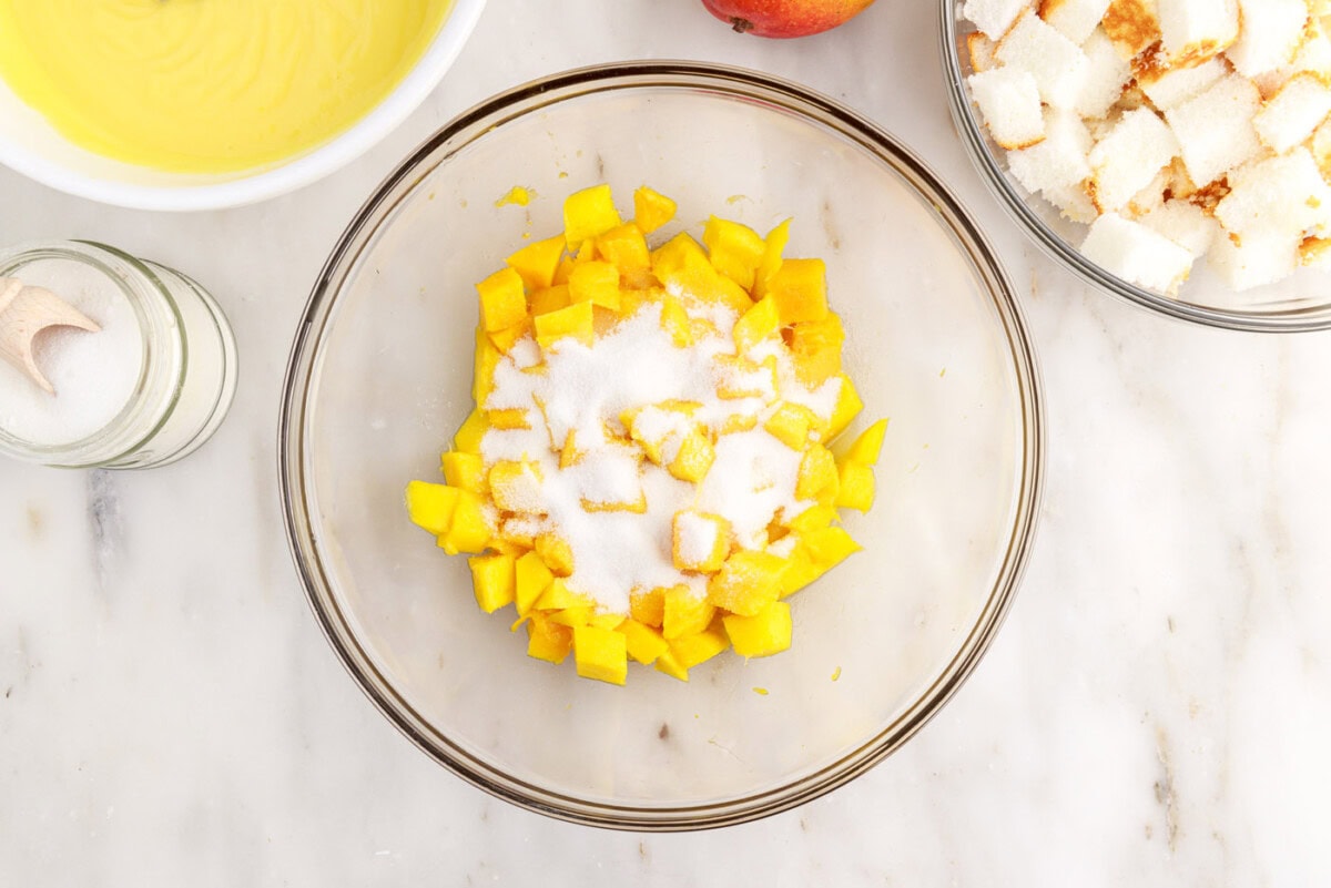 adding sugar to diced mangoes